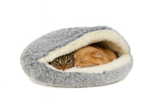 Kat ligt comfortabel in een grijze pluche donutmand met kap die warmte vasthoudt en stress vermindert.